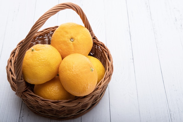 tangerines in a basket on white wooden table