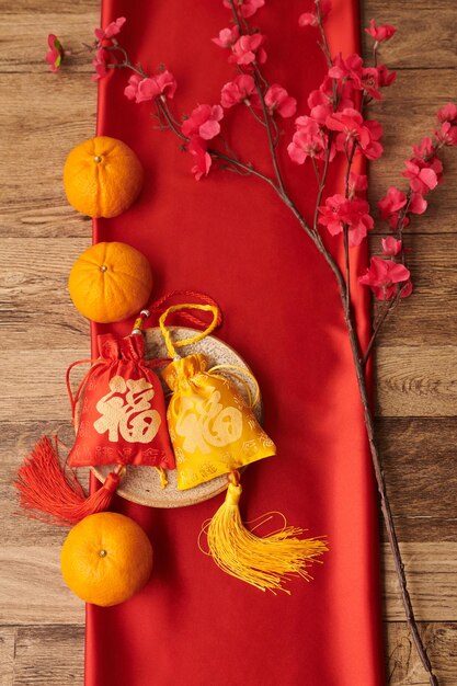 Tangerines, blooming peach branch and red and yellow small gift bags with good luck embroidery