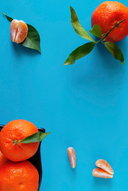 Tangerines on a blue surface next to tangerine slices.