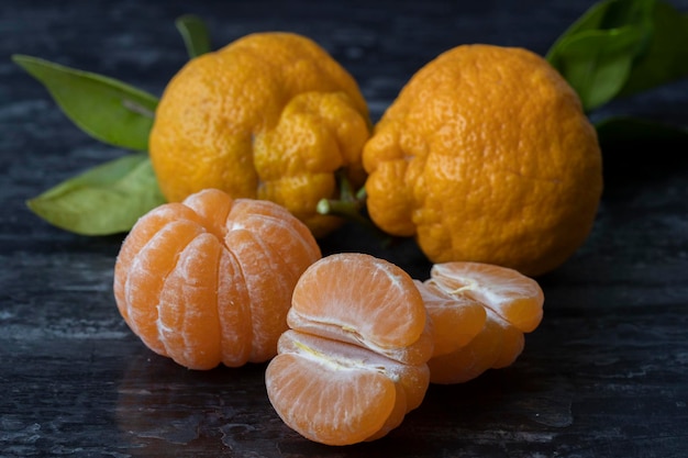 Photo tangerines or clementines with green leaves on black background