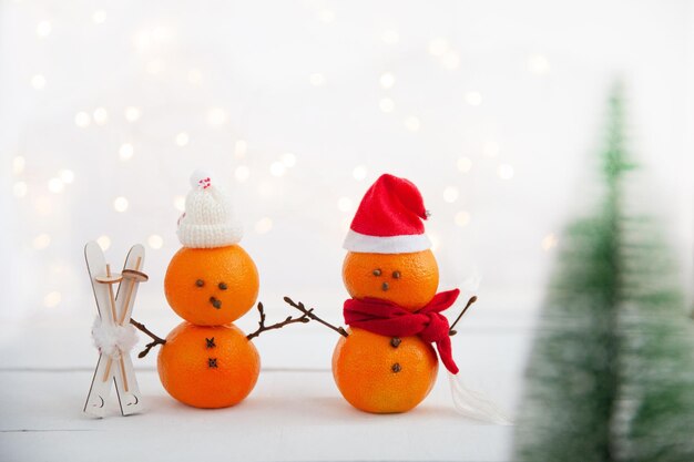 Foto tangerine a forma di pupazzi di neve con sci di legno su uno sfondo chiaro concetto di vacanze invernali