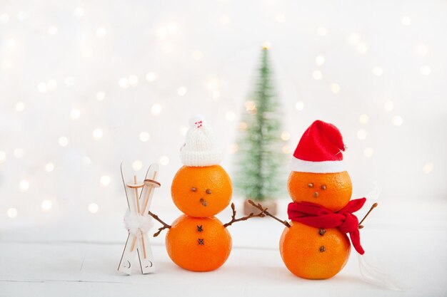 Foto tangerine a forma di pupazzi di neve con sci di legno su uno sfondo chiaro concetto di vacanze invernali