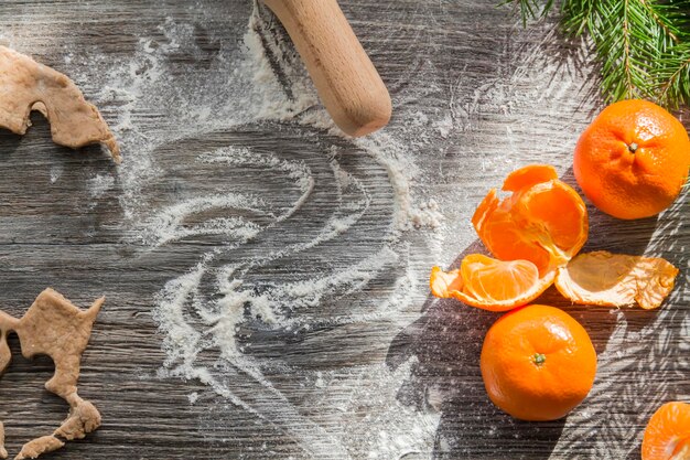 Tangerines gingerbread and cookies on a wooden table sprinkled with white flour in the form of snow