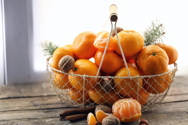 Tangerines in metal basket, on old wooden table, close up