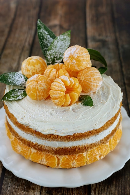 Tangerines naked cake with leaves on rustic background.