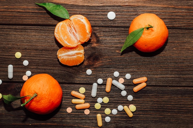 Фото Мандарины на фоне деревянного стола с витаминами и таблетками