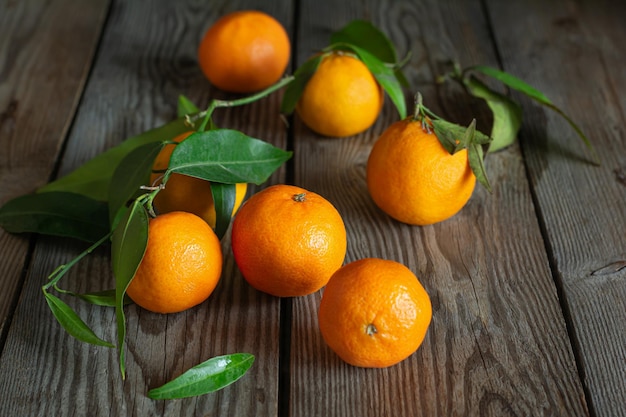 Мандарины апельсины клементины цитрусовые с листьями на деревянном фоне