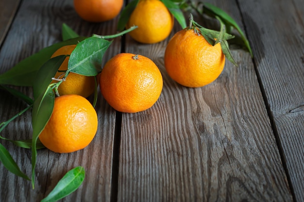 Foto tangerine arance clementine agrumi con foglie su uno sfondo di legno