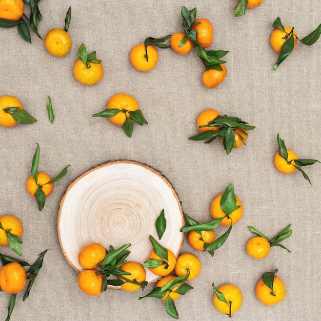 Tangerines (oranges, clementines) with green leaves on sackcloth background.