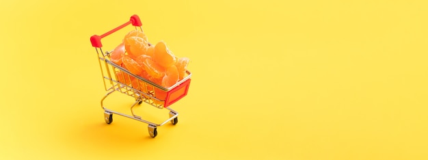 Tangerines in a shopping cart over yellow
