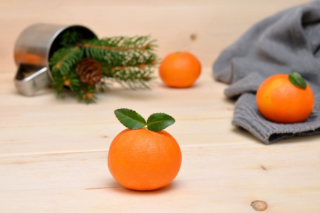 Tangerines spruce branches and a sweater scattered on a wooden background