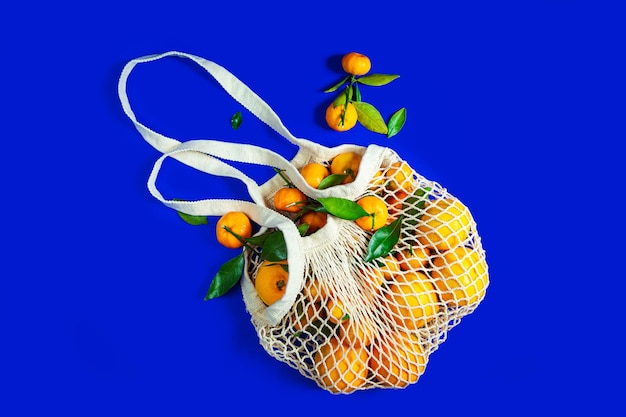 Tangerines in a string bag on a blue background