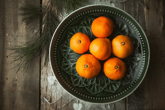 Photo tangerines and tree branches on wood table. mandarine fruits top view