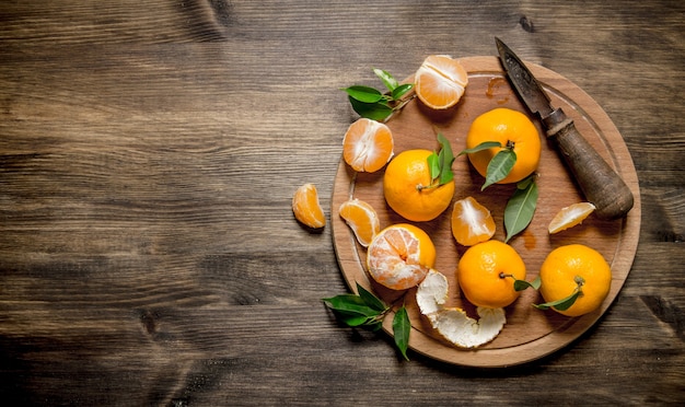 Tangerines with a knife on chopping Board on wooden table. Top view