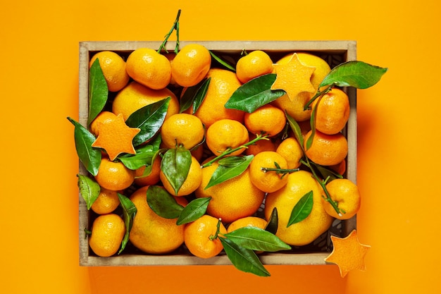 Tangerines with leaves in a box on an orange background