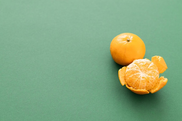 Tangerines with leaves and slices on green background