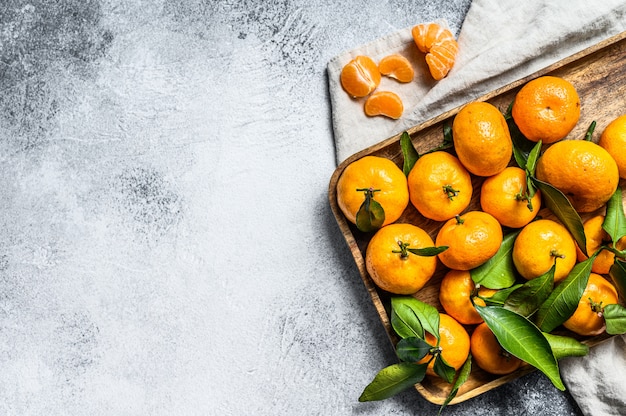 Tangerines with leaves in wooden bowl. 