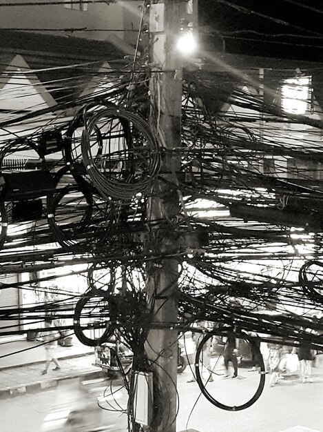 Tangled cables on pole by street at night