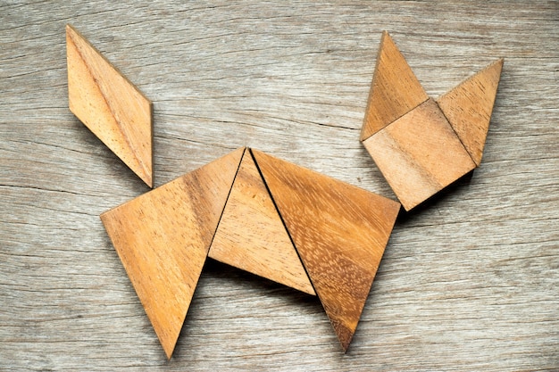 Tangram puzzle in cat shape on wooden background