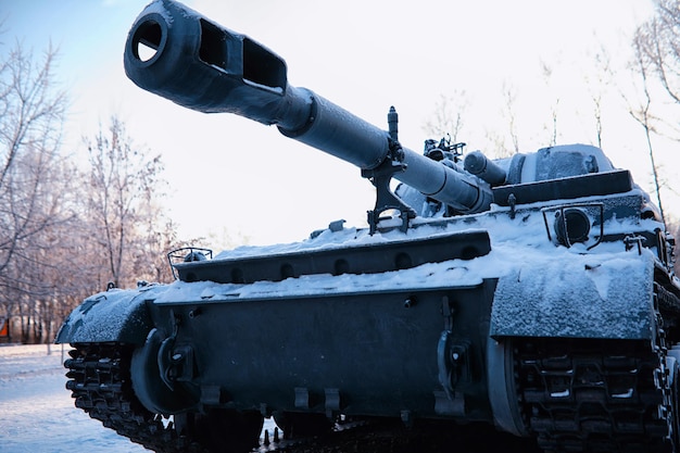 Tank onder de sneeuw in het bos Wintertankcamouflage Gevechtstank in de sneeuw langs de weg van de snelweg Oorlog in Oekraïne in de winter