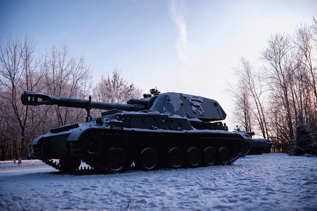 Tank onder de sneeuw in het bos wintertankcamouflage gevechtstank in de sneeuw langs de weg van de snelweg oorlog in oekraïne in de winter