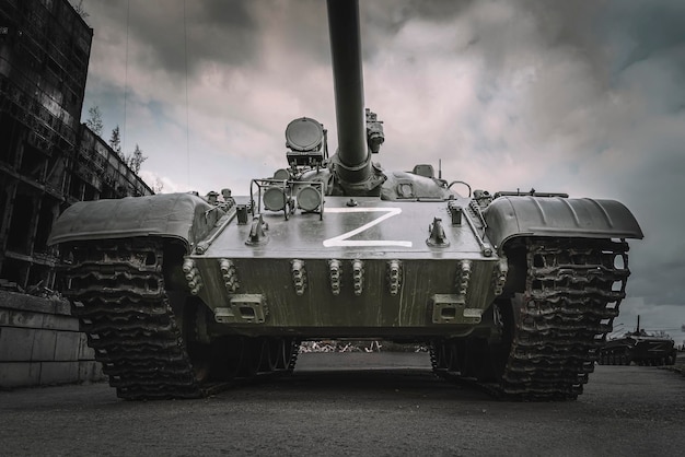 A tank with the z symbol on the background of destroyed houses The concept of confrontation between Russia and Ukraine war operation The offensive of heavy armored vehicles on streets of the city