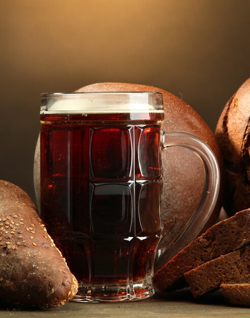 Foto tankard van kvass en roggebrood op houten tafel op bruine achtergrond