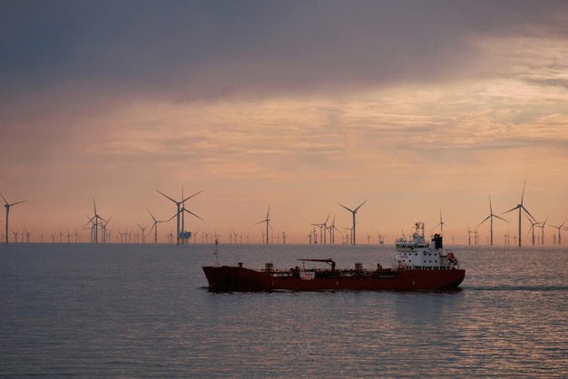 tanker underway during calm weather in the North Sea with a park of wind generators in the backgroun