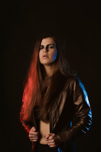 붉은 빛으로 스튜디오에서 포즈를 취하는 창의적인 화장을 한 검게 그을린 갈색 머리 여자
