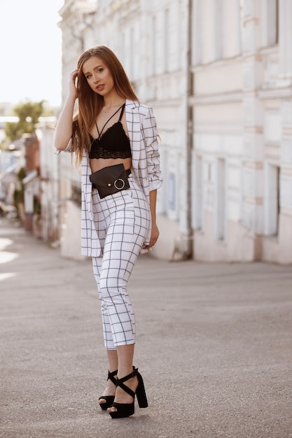 Tanned girl in a white suit on a background of the city in summer. bluer