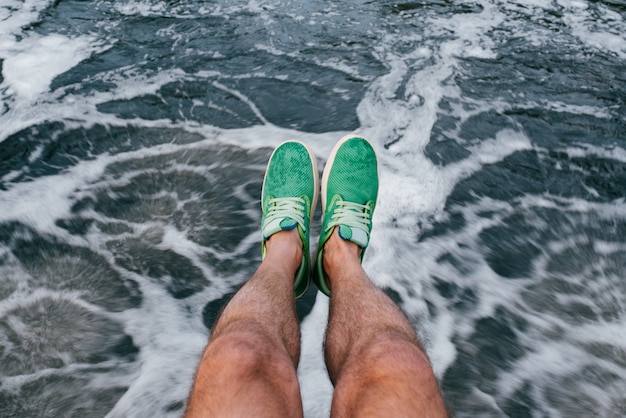 Tanned male legs in green summer sneakers