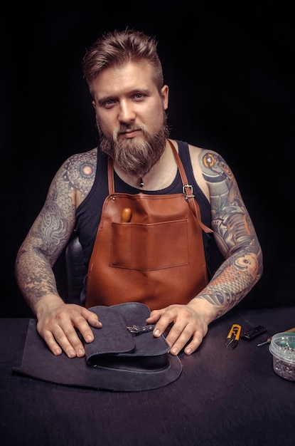 Tanner creates a new leatherwork at the leather shop./Leather Artisan at work on his new leather product .