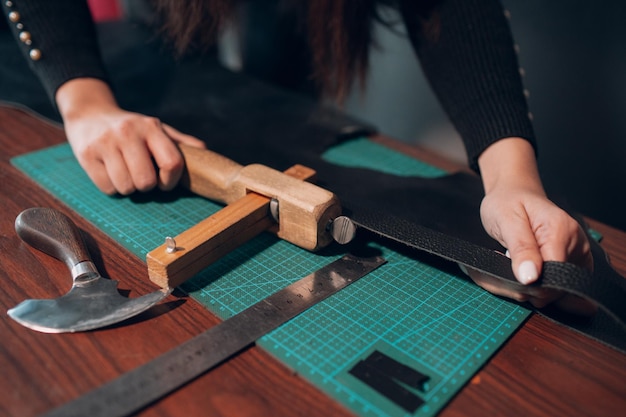 Tanner woman cutting leather goods on workshop working process of leather craftsman