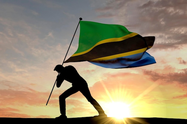 Tanzania flag being pushed into the ground by a male silhouette 3D Rendering