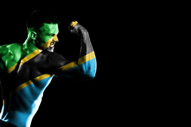 Tanzania flag on handsome young muscular man black background