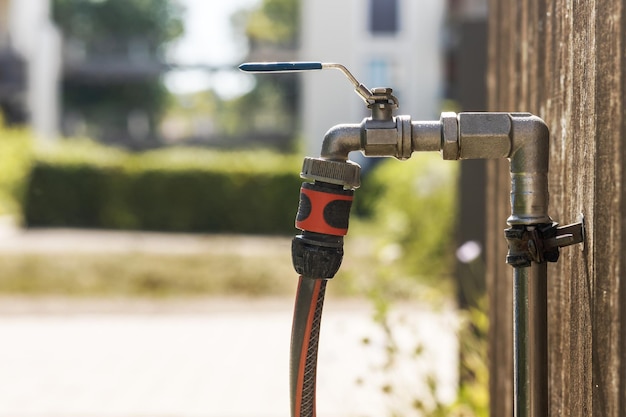 Tap Hose Outside. Water Hose connected to Pipe with  Faucet on wall. Garden Watering equipment.