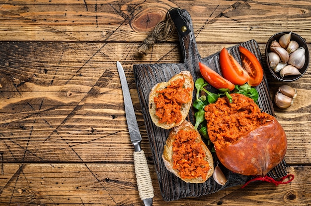 Tapaasandwiches met Sobrassada gezouten varkensworst en tomaat op een houten snijplank. houten achtergrond. Bovenaanzicht. Ruimte kopiëren.