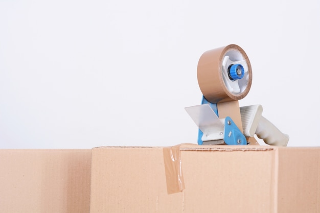 Tape dispenser sealing a shipping cardboard box