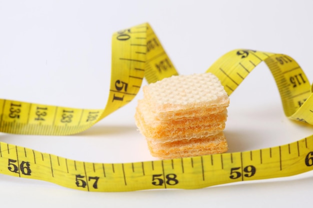 Tape measure and cheese biscuit isolated on white background\
diet and healthy concept