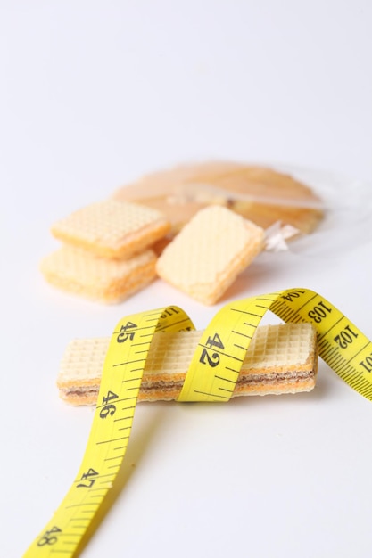 Tape measure and cheese biscuit isolated on white background\
diet and healthy concept