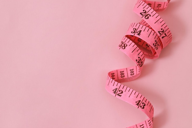 tape measure for obese people on a pink background soft focus