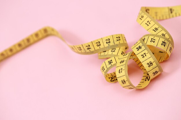 Photo tape measure for obese people on a pink background soft focus