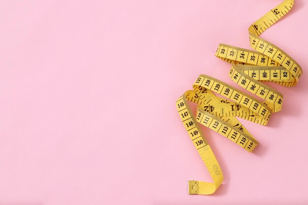 Foto nastro metrico per persone obese su uno sfondo rosa messa a fuoco morbida