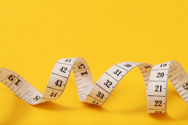 Tape measure for obese people on a yellow background soft\
focus