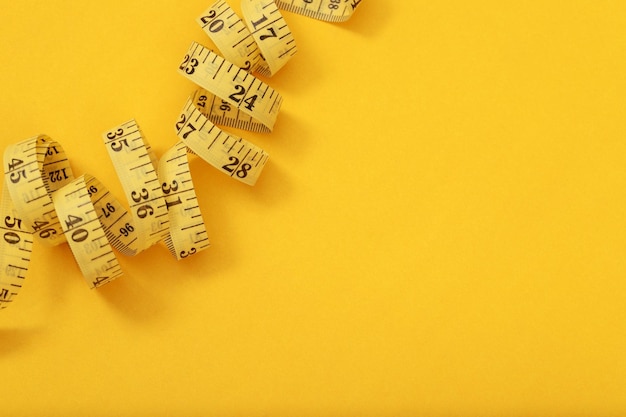 Photo tape measure for obese people on a yellow background soft focus