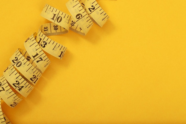 Photo tape measure for obese people on a yellow background soft focus