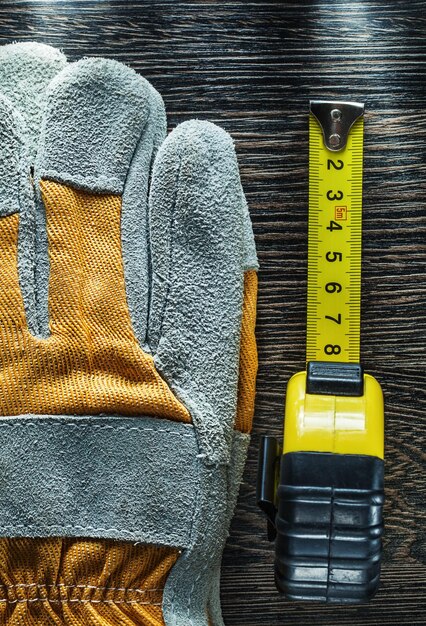 Foto misura di nastro paio di guanti di sicurezza su tavola di legno