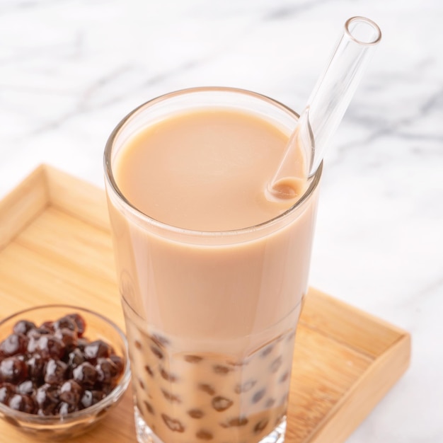 Tapioca parel bal bubbel melk thee populaire Taiwan drankje in drinkglas met stro op marmeren witte tafel en houten dienblad close-up kopie ruimte