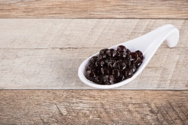 Tapioca Pearl , Bubble topping for tea or other beverage, in a cup, place on wooden table. Copy space