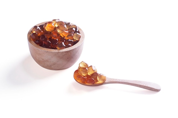 Tapioca Pearls Bubble Tea on wooden spoon and bowl isolated on white background It's small chewy balls made from tapioca starch Commonly used as a topping in milk tea drinks